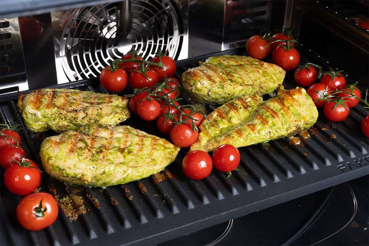 pesto chicken on a grille plate with tomato