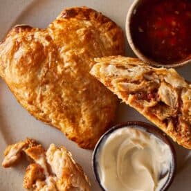 A top down view of a heart shaped tart and a half hart tart sliced in 2 with marry us chicken stuffing inside. A tomato sauce relish in a jar on the side.
