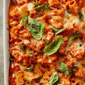 Tomato soup mac and cheese baked until golden and bubbly, made with rigatoni pasta in a rich roasted tomato sauce, topped with melted cheddar and mozzarella, and finished with fresh basil leaves.