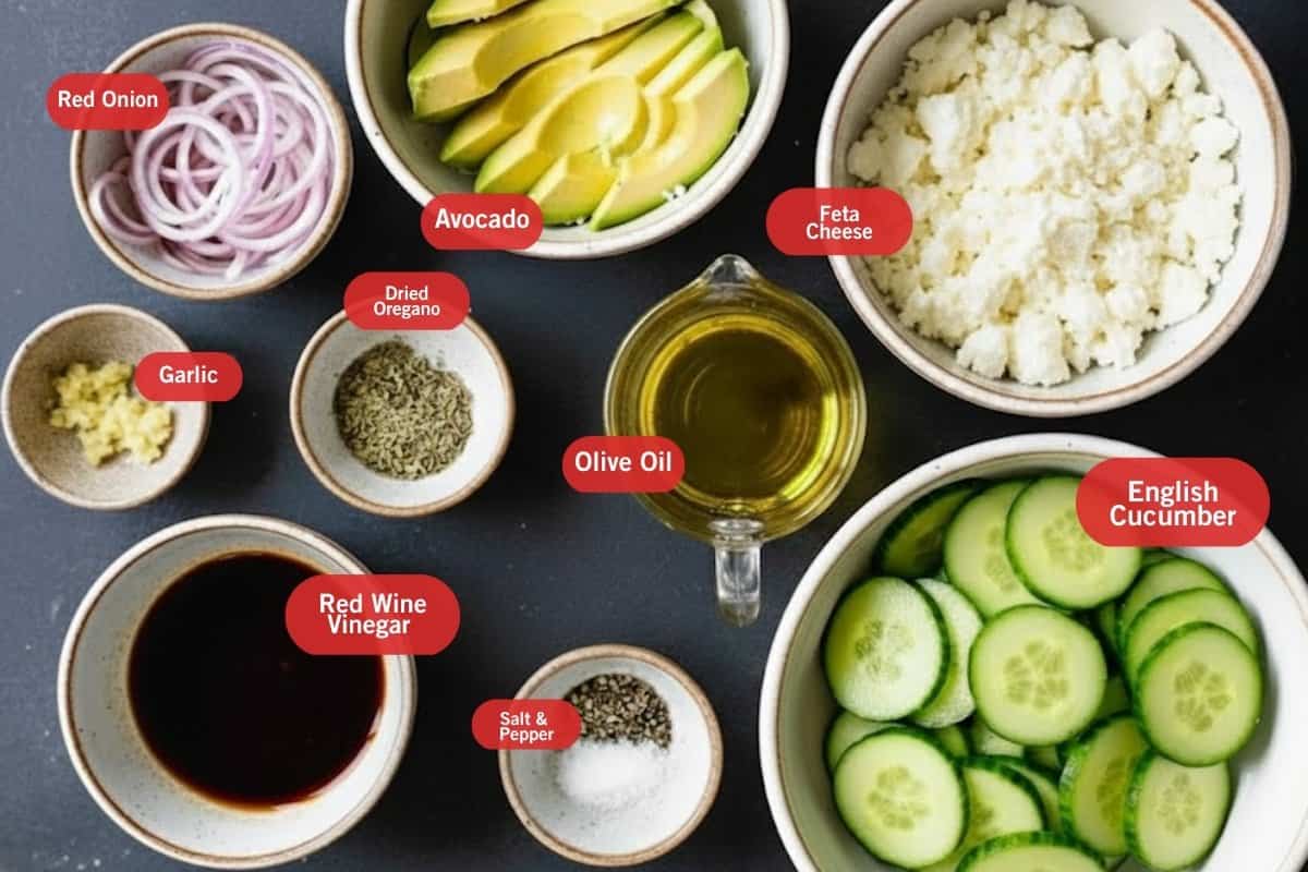 Flat lay photo of ingredient shot of red onion, avocado, feta cheese, garlic, olive oil dried oregano, olive oil, English cucumber, salt and pepper, red wine vinegar