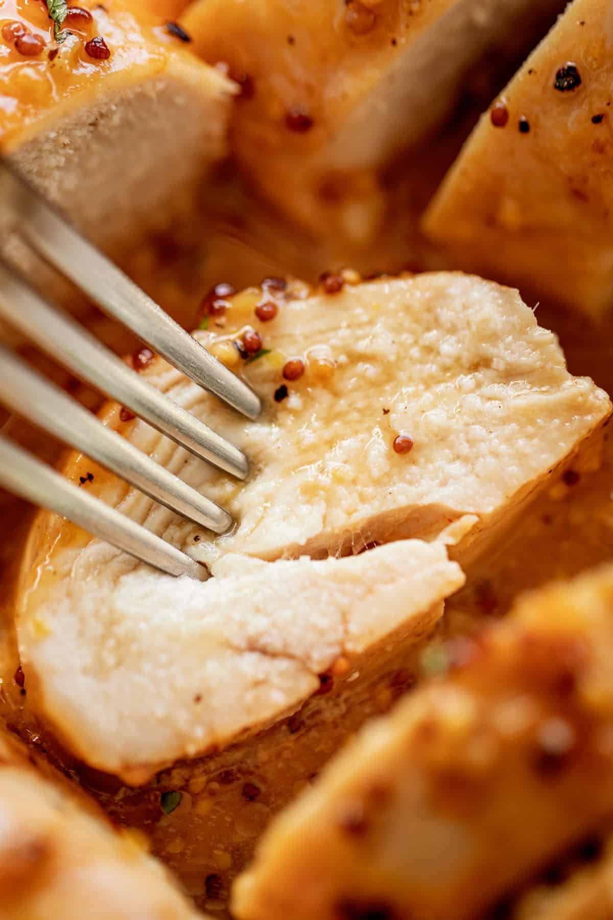 A slice of tender and juicy Baked Chicken Breasts with a good honey mustard sauce.