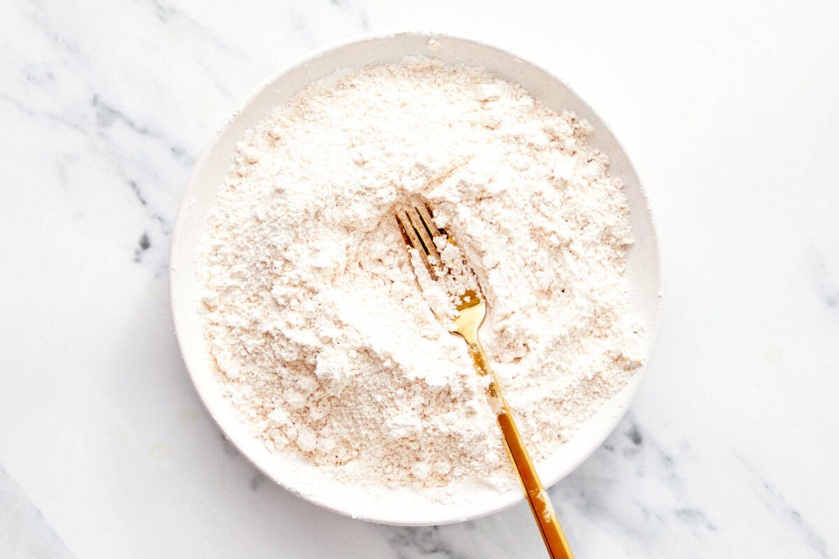 White bowl filled with seasoned cornstarch and breadcrumbs mixture with a fork