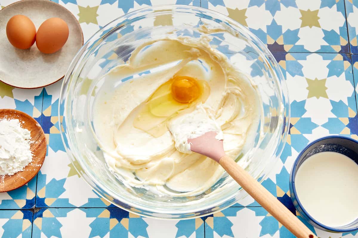 Egg being mixed into creamy cheesecake batter