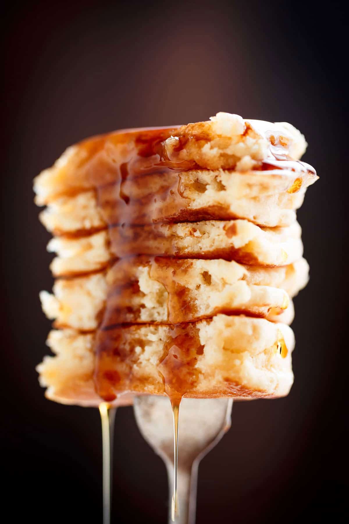 A piece of Best Fluffy Pancakes in a fork are right here! Weekends will never be the same again!