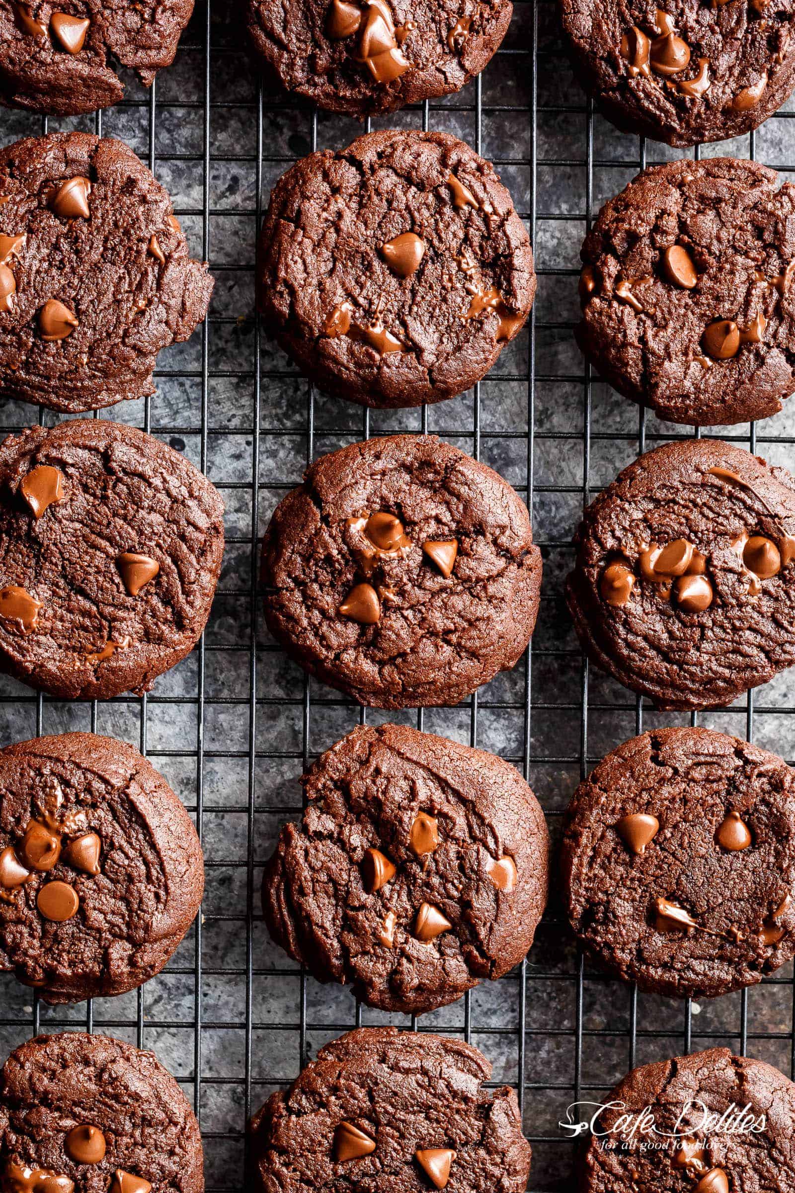 Bird\'s eye view of finished cookies with some chocolate chips in the middle on a cooling rack with shiny chocolate chips visible across the surface of each one.