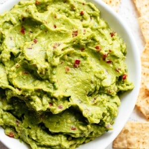 Top view of a reliable, creamy Guacamole is so easy to make and better than anything found in a jar! Homemade Guacamole takes minutes to make and is so incredibly good! good for a party as an appetizer OR just a simple snack! Use as a topping for your favourite fajitas, tacos and even carnitas.