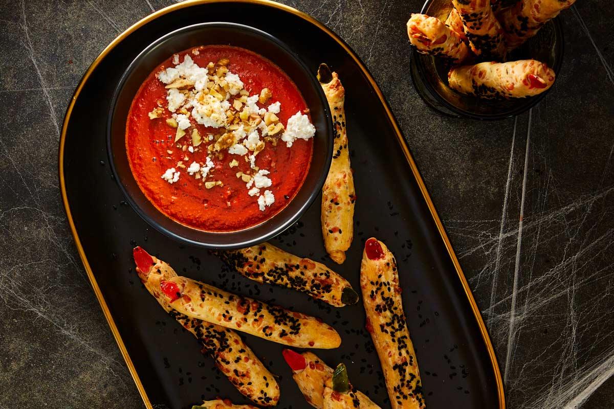 Blender filled with roasted red sauce, feta cheese, and walnuts ready to blend into a smooth, creamy dip.