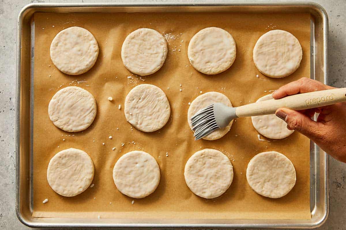 Round pieces of dough being brushed with remain buttermilk |