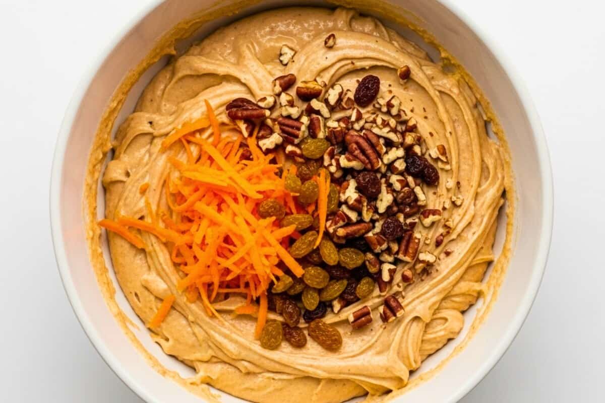 Fold in the grated carrots, nuts and raisins to the wet mixture