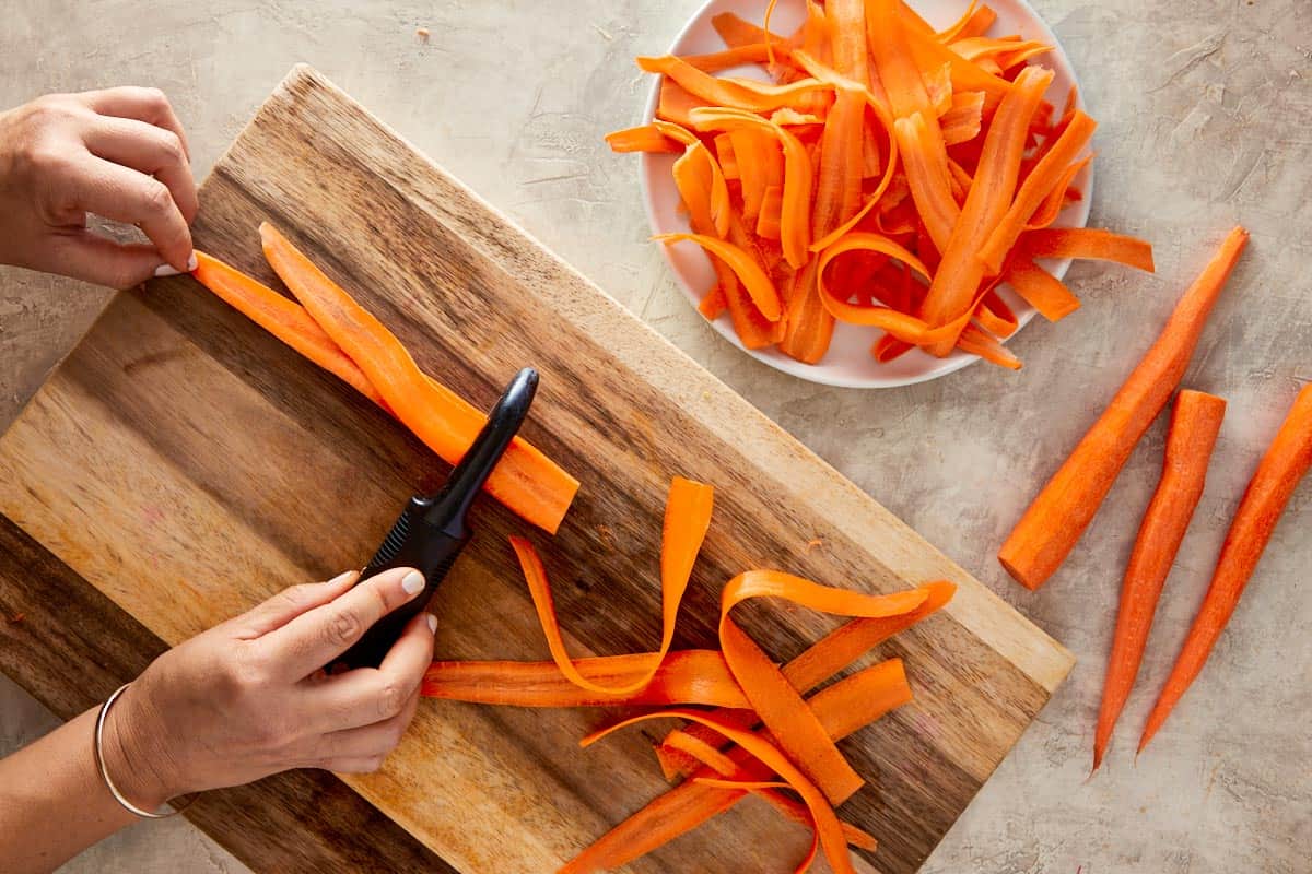 carrots being shredded with a peeler