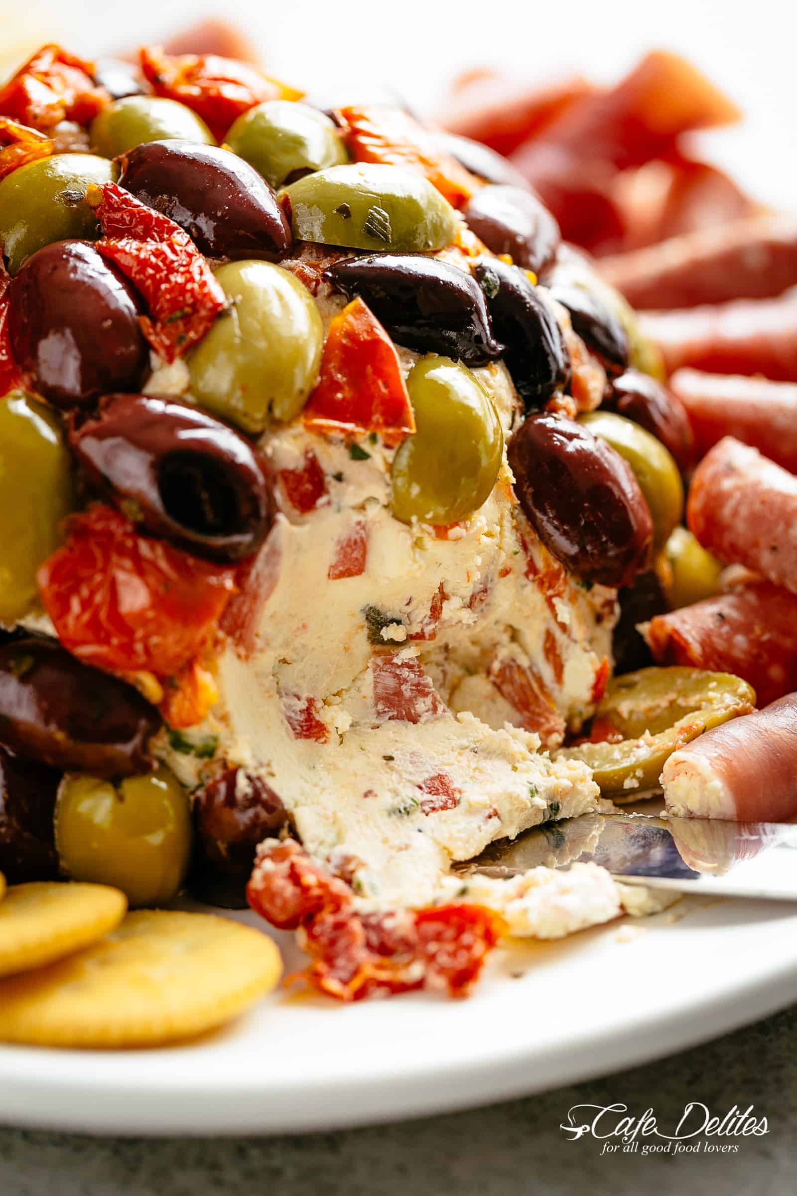 A bite taken from Antipasto-Cheeseball on a plate