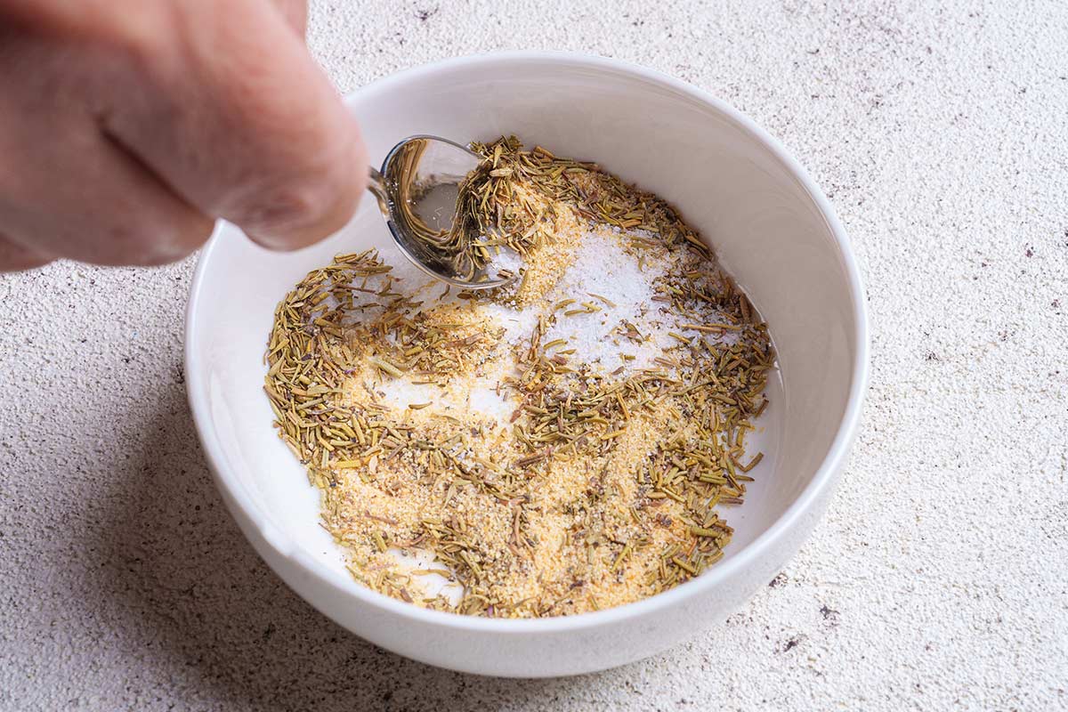 In a white bowl, onion powder, garlic powder, dried herbs, salt and pepper are combined