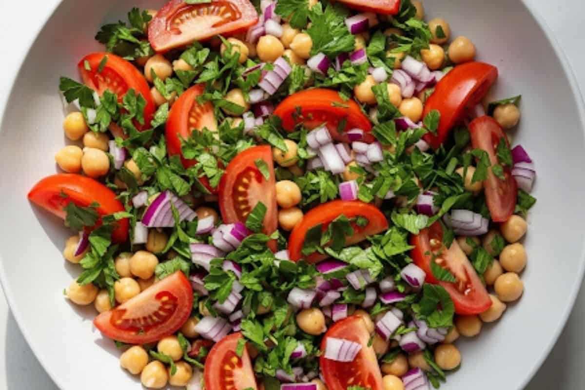 In a large bowl, combine the chickpeas, quartered tomatoes, chopped parsley and finely diced red onion.
