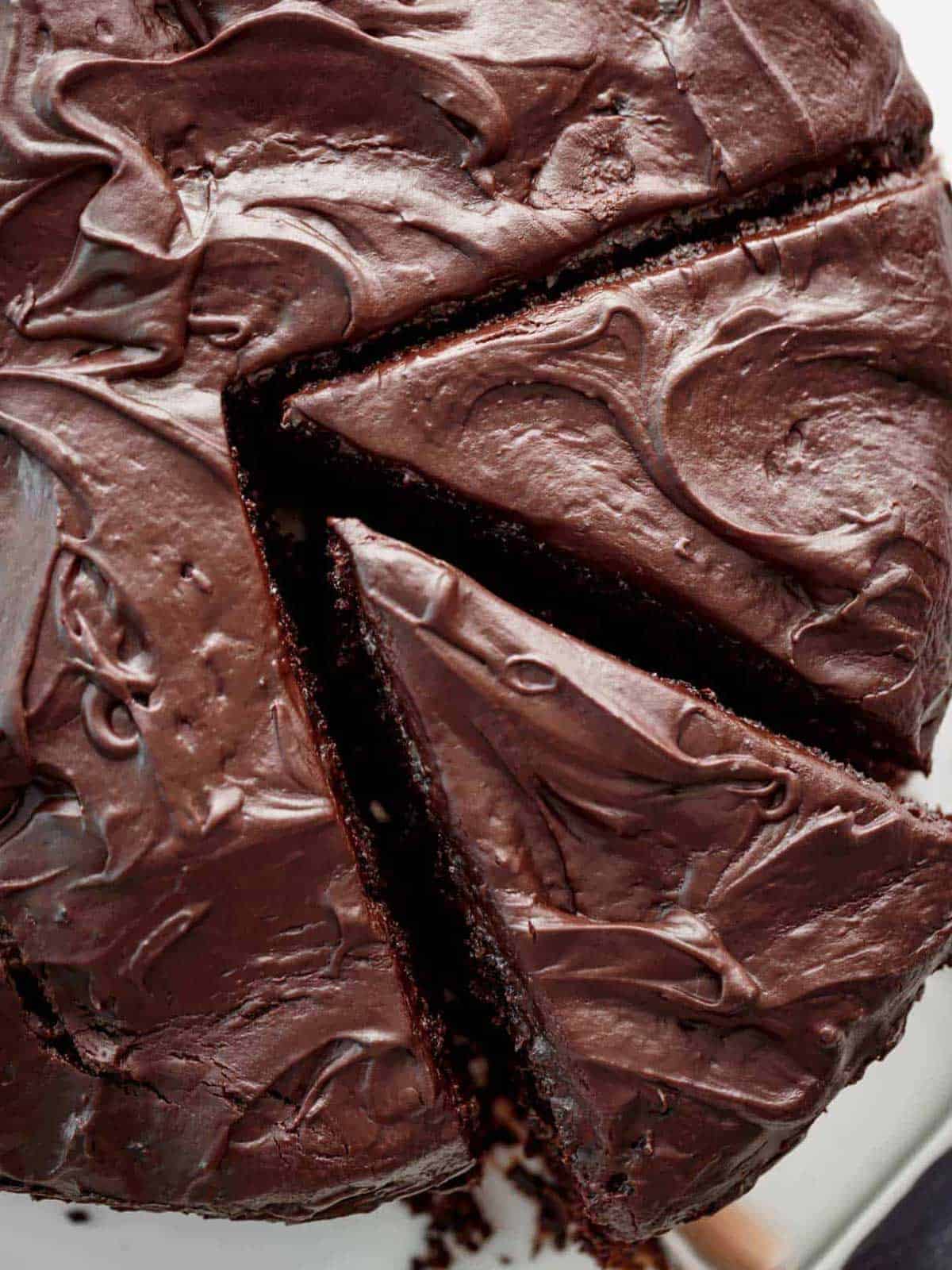 A thick chocolate cake lathered with chocolate butter cream with two pieces cut ready for serving
