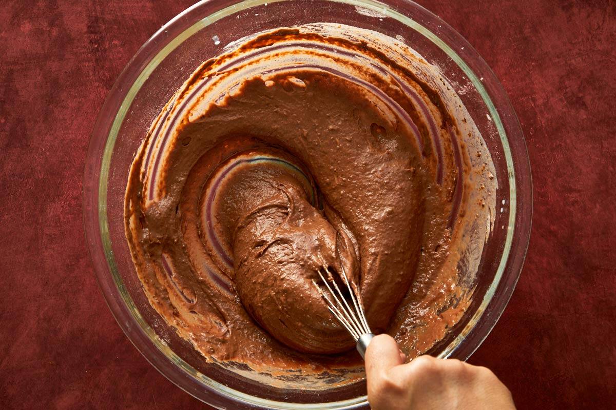 Mixing chocolate cake batter until smooth and silky with a whisk.