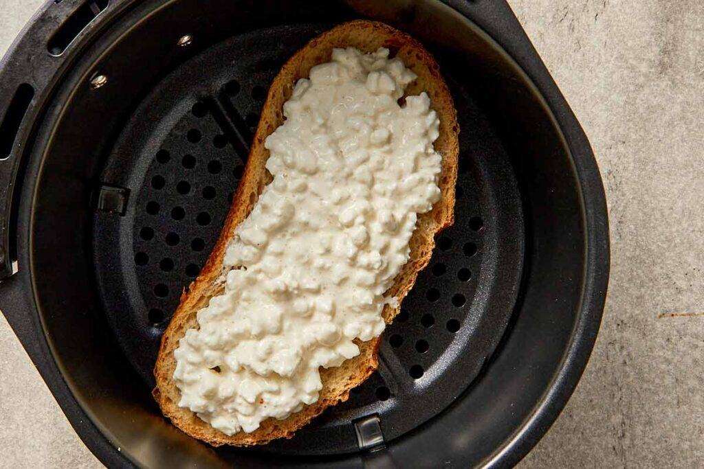 Cottage cheese toast on sourdough placed in an air fryer basket ready to cook.