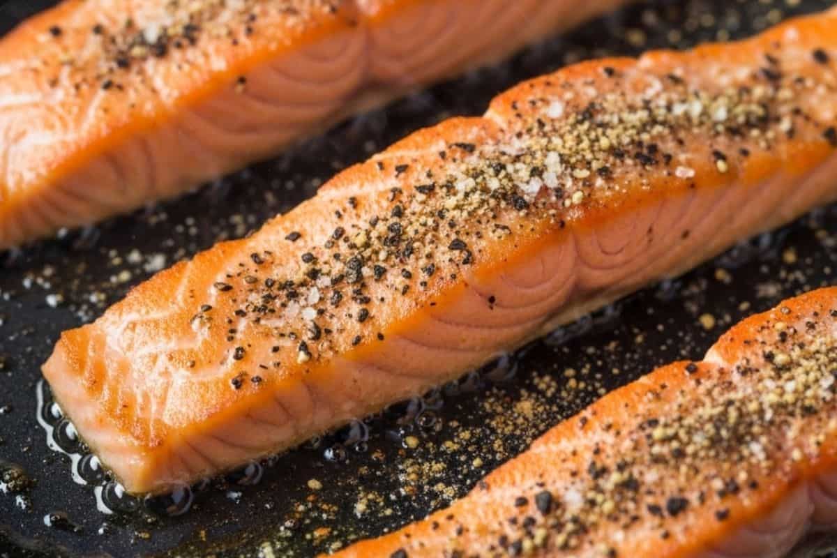 In a large skillet over medium high heat, season the salmon with salt, pepper and garlic powder for 5 minutes until golden.