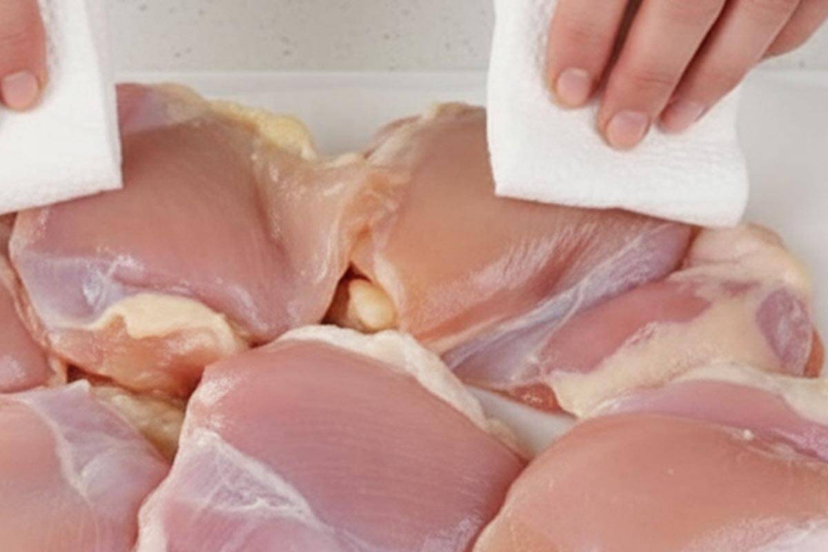 Patting the chicken dry using paper towel.