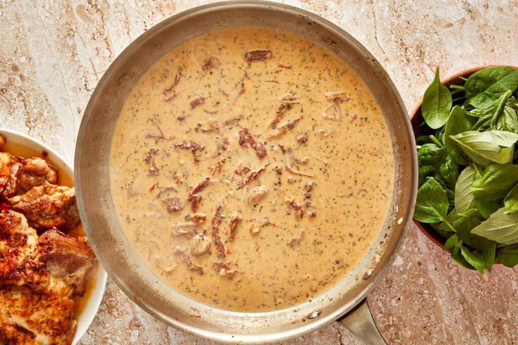 a top down shot of a bowl with a thick brown sauce inside, and what looks like sun-dried tomatoes swimming in the sauce