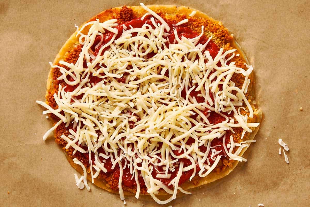 Mozzarella cheese added over tomato sauce on chicken tortilla