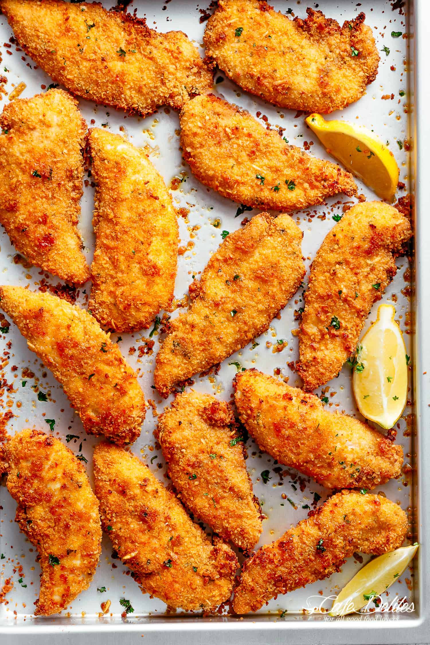 Chicken Tenders on a baking pan with garlic, lemon and parmesan breading.