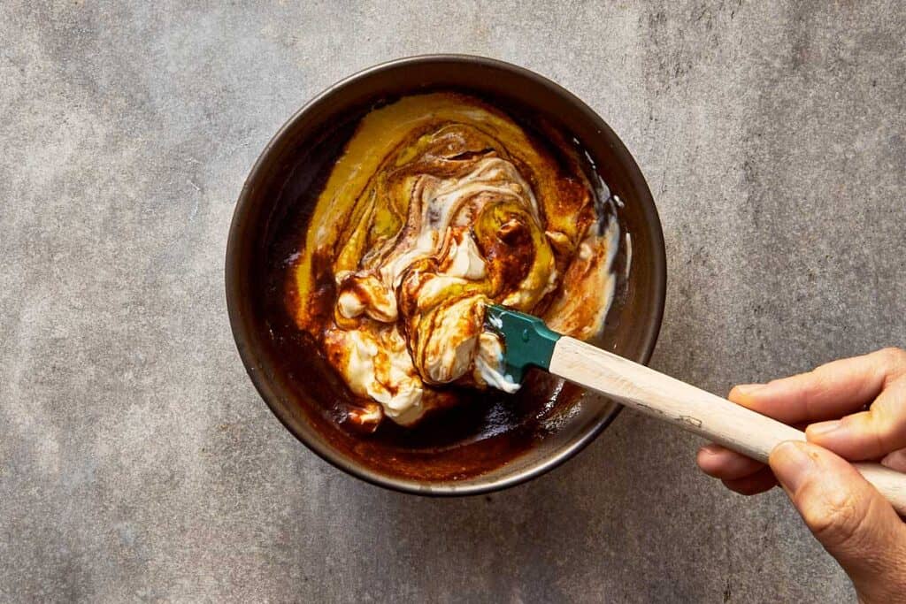 a top down view of a bowl of sauce being stirred by a spoon