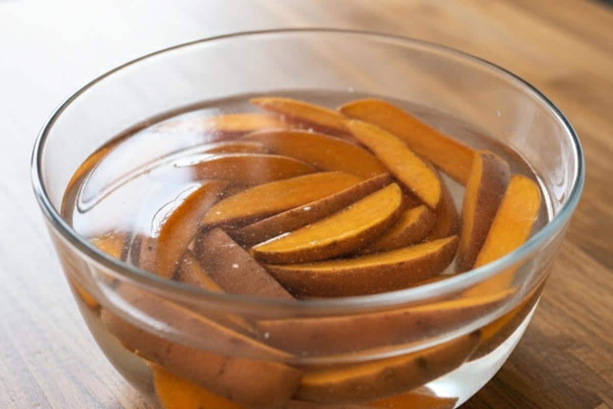 Sweet potato wedges in a large bowl of cold water.