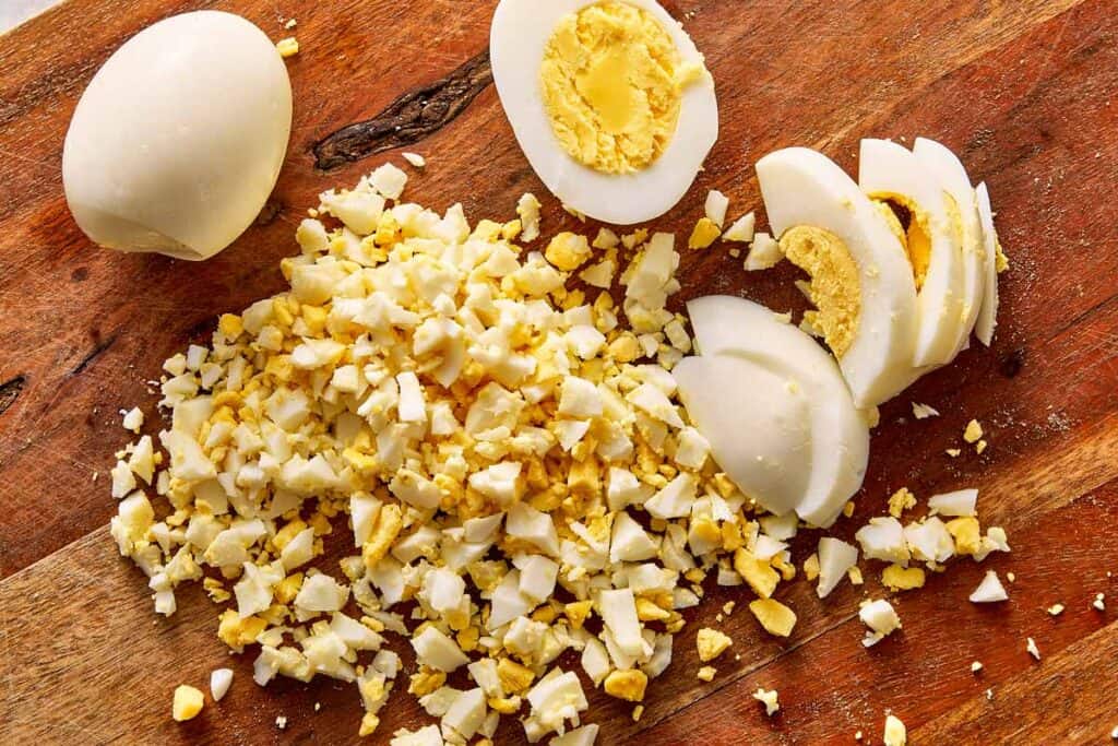 Finely chopped hard-boiled eggs on a cutting board for deviled potato filling