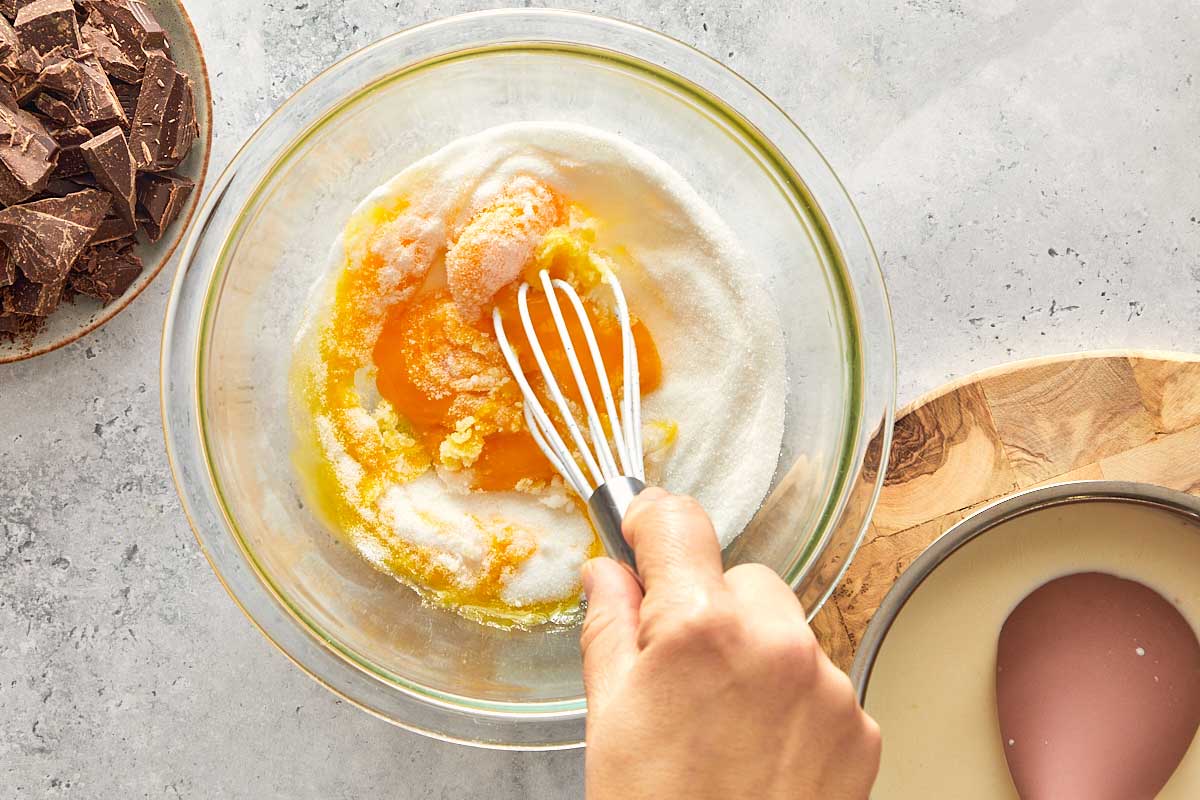 cream and egg mix in a mixing bowl top down view being whisked together