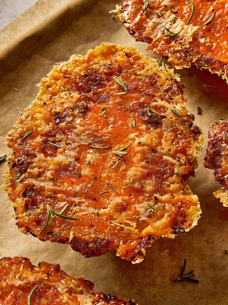 Crispy baked sweet potato with golden Parmesan crust and herbs on a lined tray