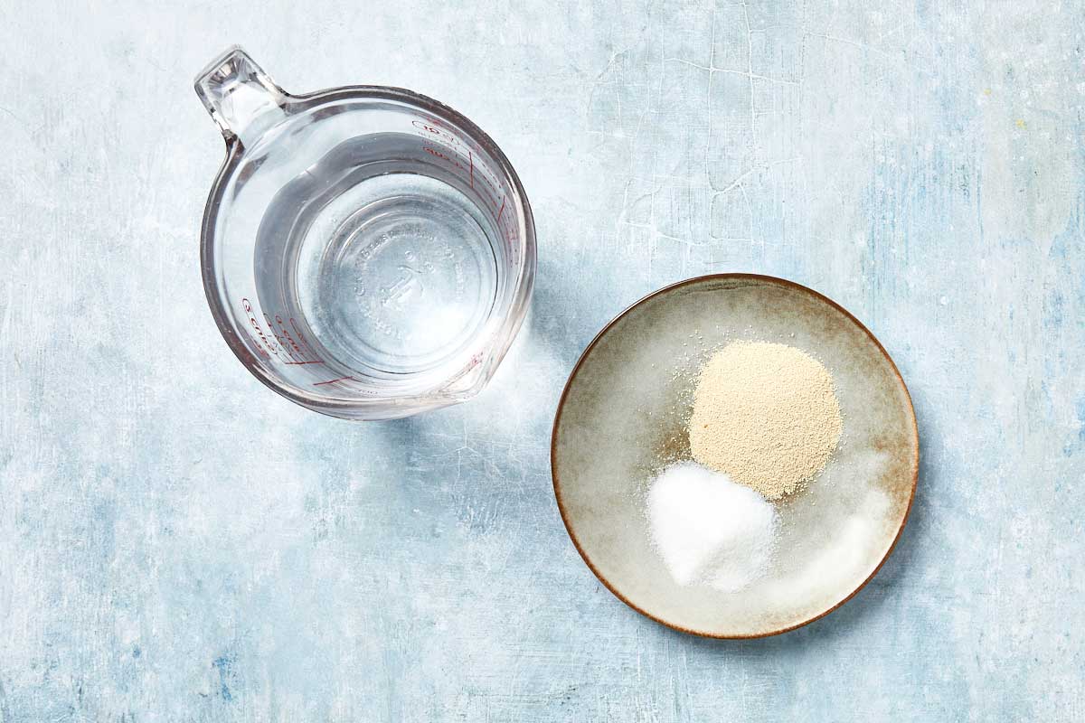Yeast, sugar, and warm water shown together in preparation for blooming.