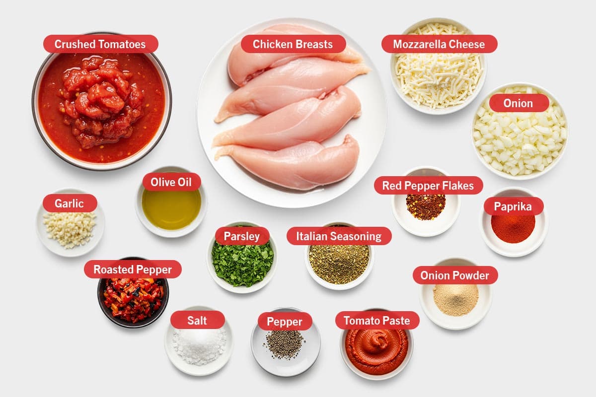 Top shot of ingredients: Crushed tomatoes, chicken breasts, mozzarella cheese, onion, garlic, olive oil, roasted pepper, salt, parsley, pepper, Italian seasoning, tomato paste, red pepper flakes, onion powder, and paprika.