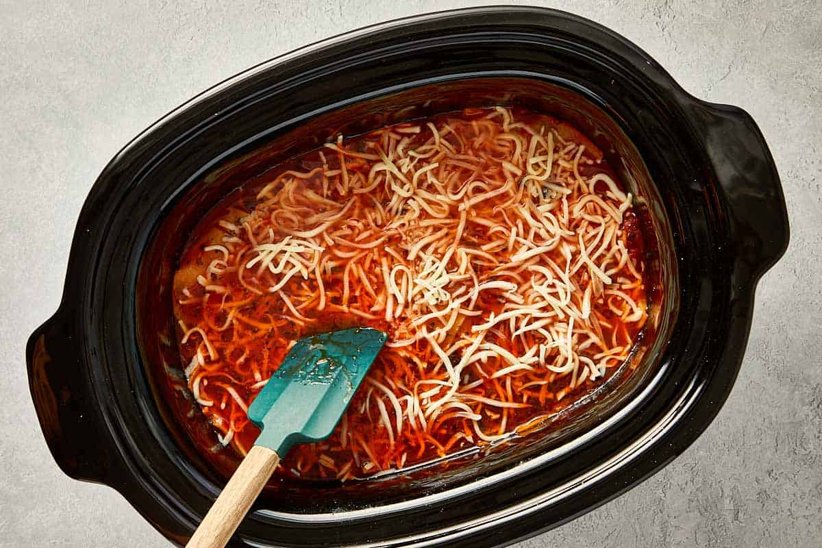top overview of cheese being added into the lasagna soup in the slowcooker.