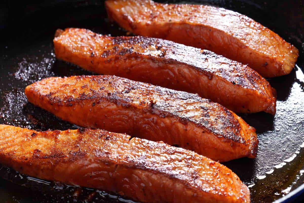 Image of the salmon being seared in a skillet and cooked on both sides to achieve a good, nice crust.