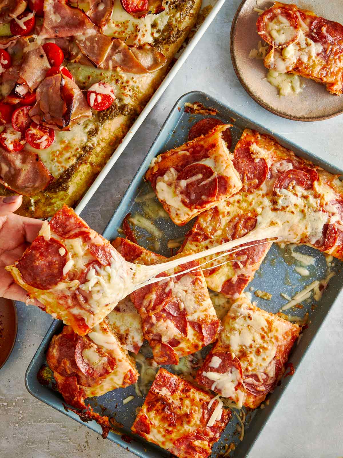 Hand pulling a cheesy slice of focaccia pizza.