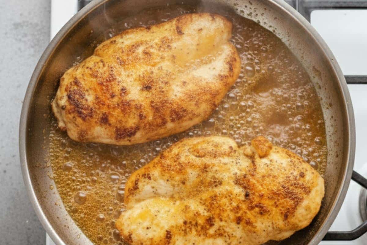 Frying the chicken coated with flour mixture.