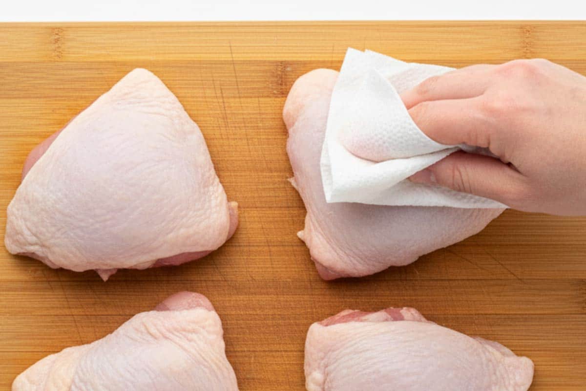 Patting the chicken dry using paper towel.