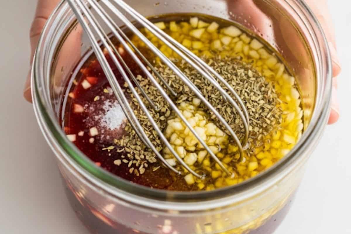 In a jar, whisk together olive oil, red wine vinegar, minced garlic, oregano and salt