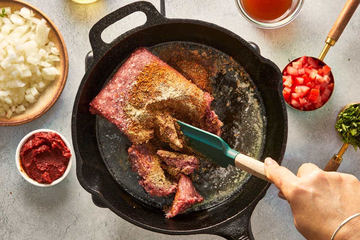 Ground beef with spices cooking in a cast iron skillet