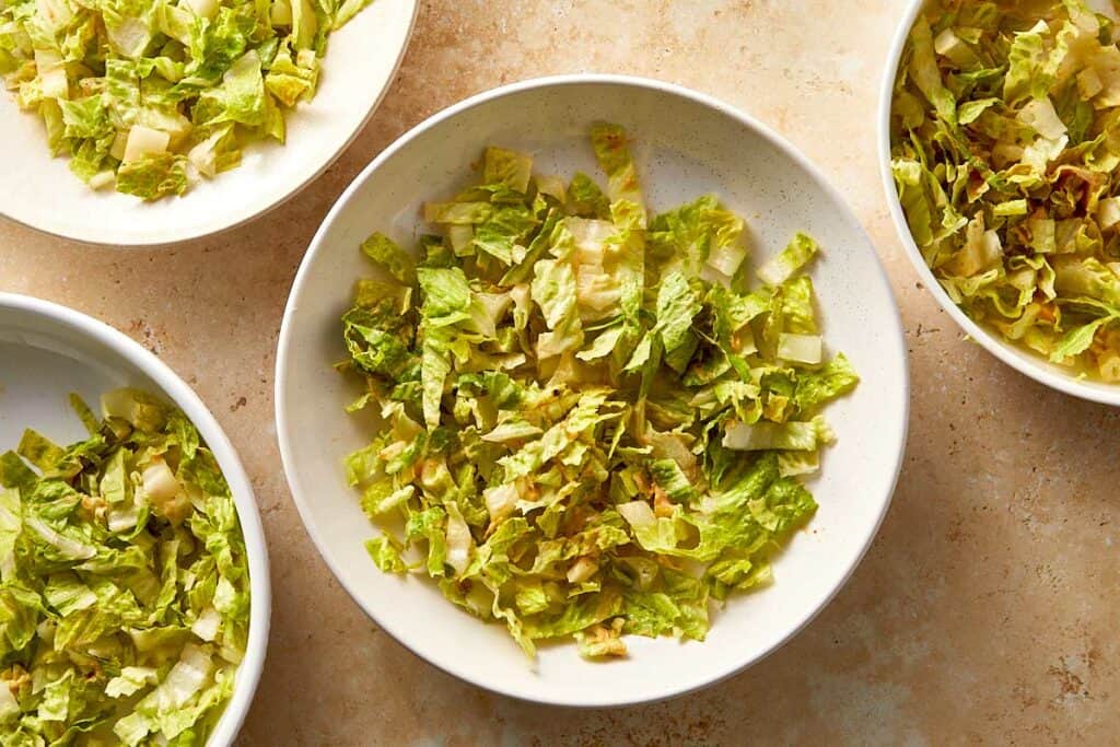 Chopped lettuce portioned into bowls as the base for burger bowls.