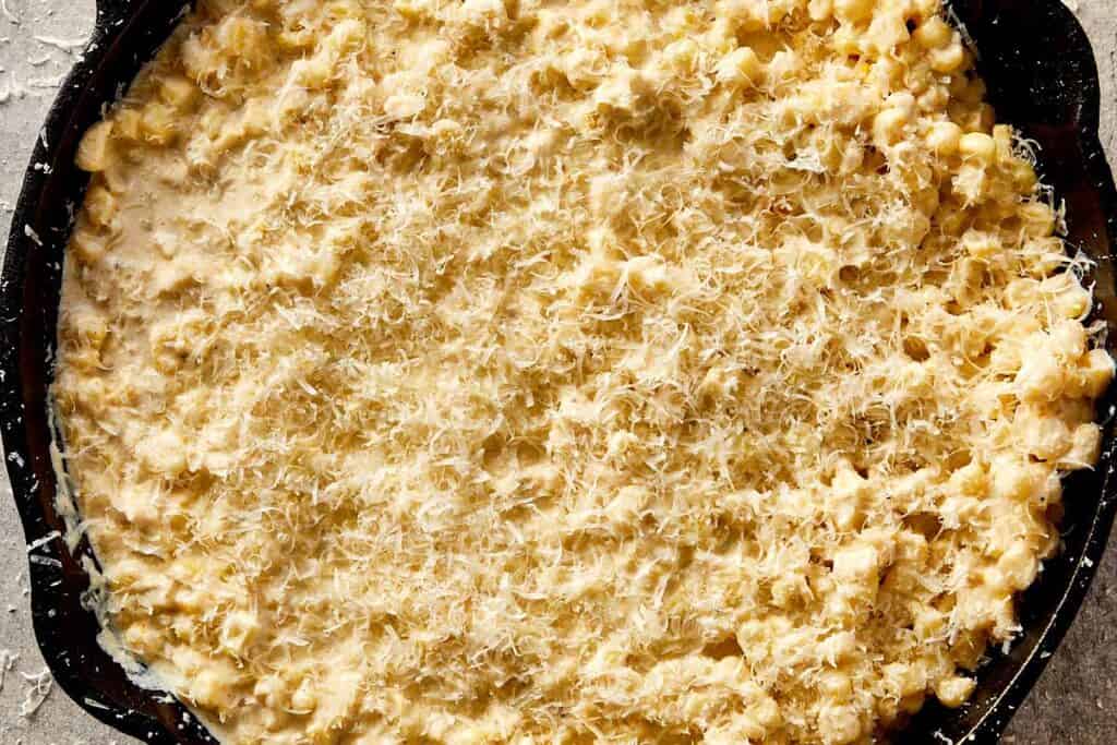 Creamy corn topped with grated parmesan, ready to broil until golden and slightly crisp