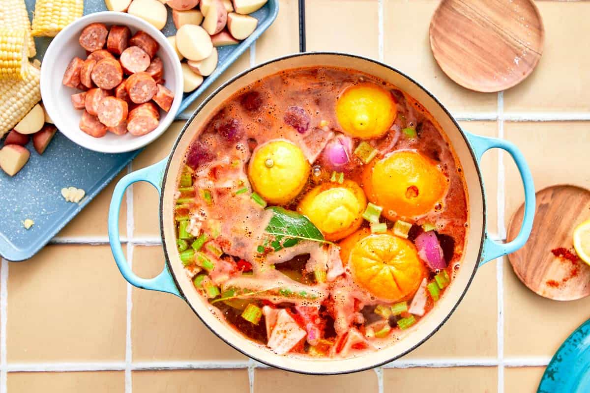 Pot filled with broth, citrus halves, and aromatics simmering over the stove.