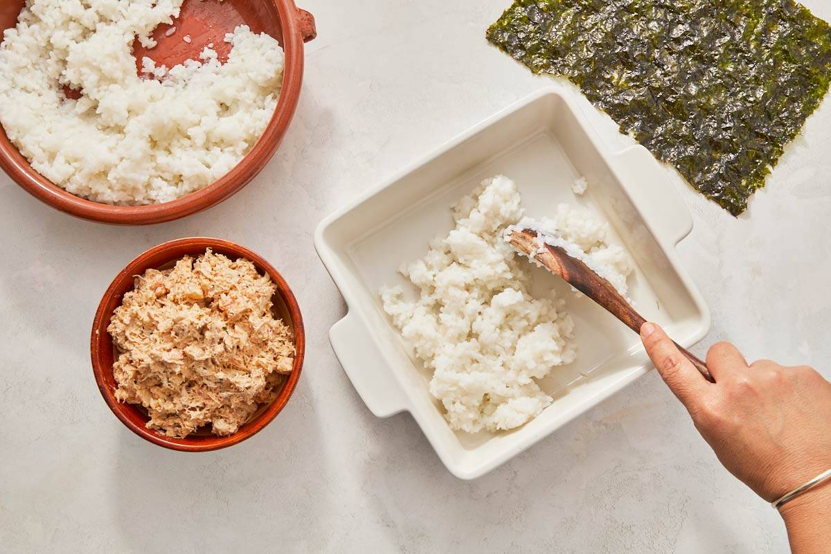 Stirring rice into a bowl with a spoon, layering it