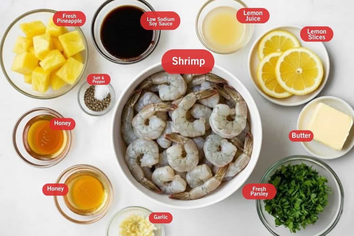 Flat lay photo of ingredient shot of fresh pineapples, low sodium soy sauce, lemon juice, lemon slices, butter, fresh parsley, shrimp, salt and pepper, honey, garlic