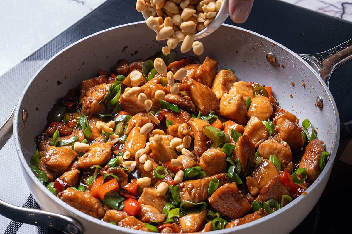 garlic, ginger, chili diced peppers (capsicums) and Sichuan peppercorns and chicken with peanuts being poured over