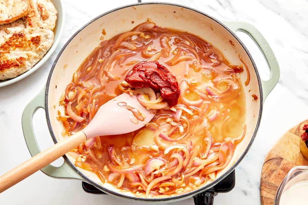 Stirring in cream, sun-dried tomatoes, and basil to finish the sauce.