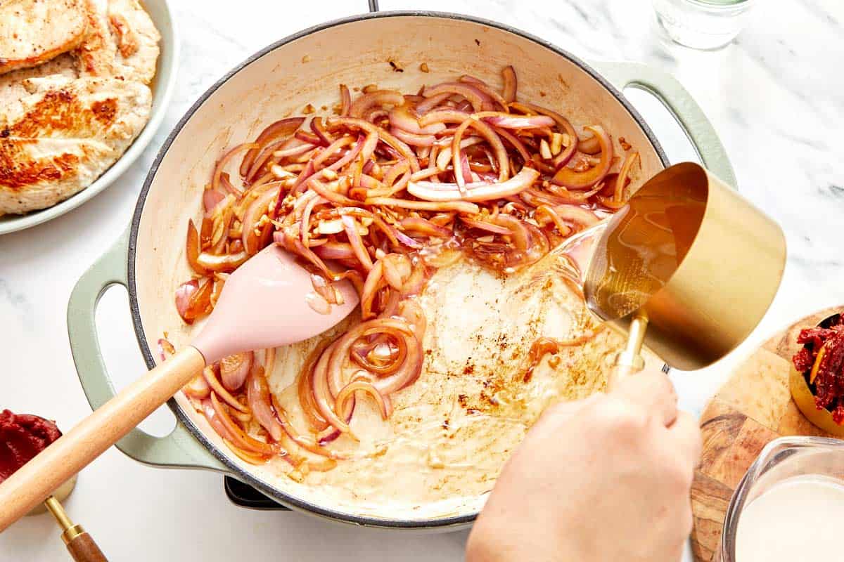Scraping up browned bits from the skillet with a wooden spoon.