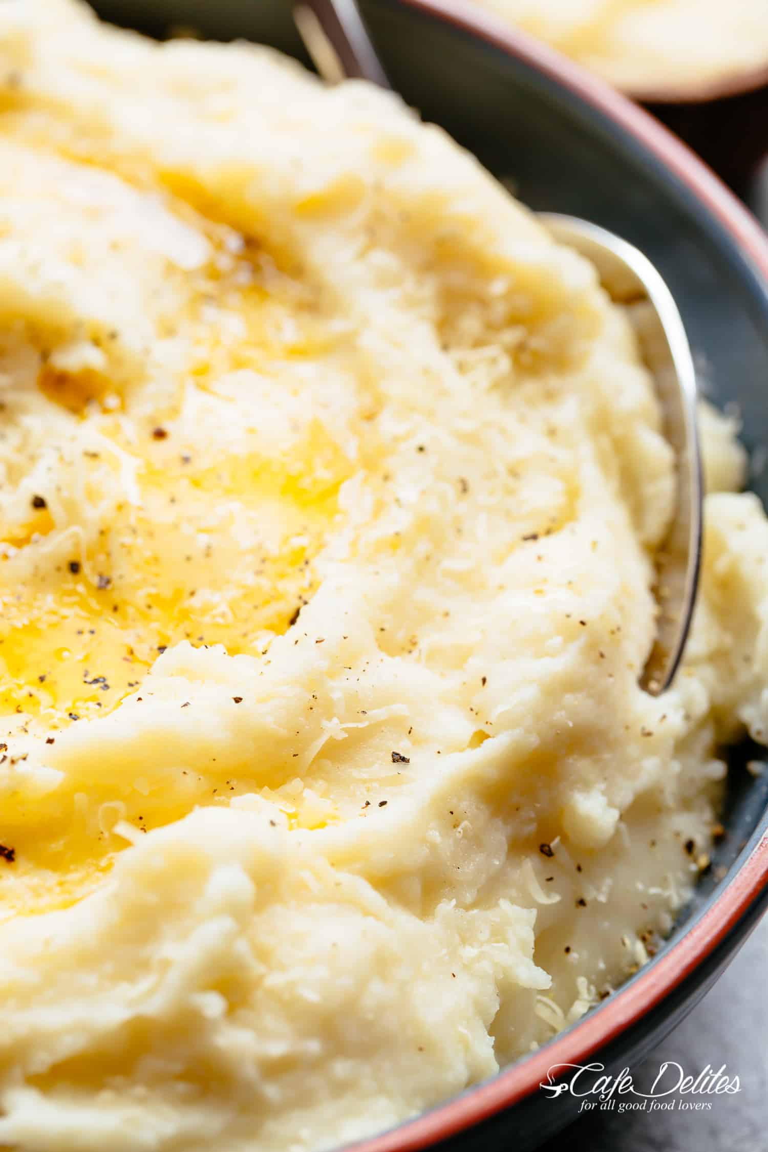 Close-up image of buttery cauliflower topped with parmesan, oil, and cracked pepper.