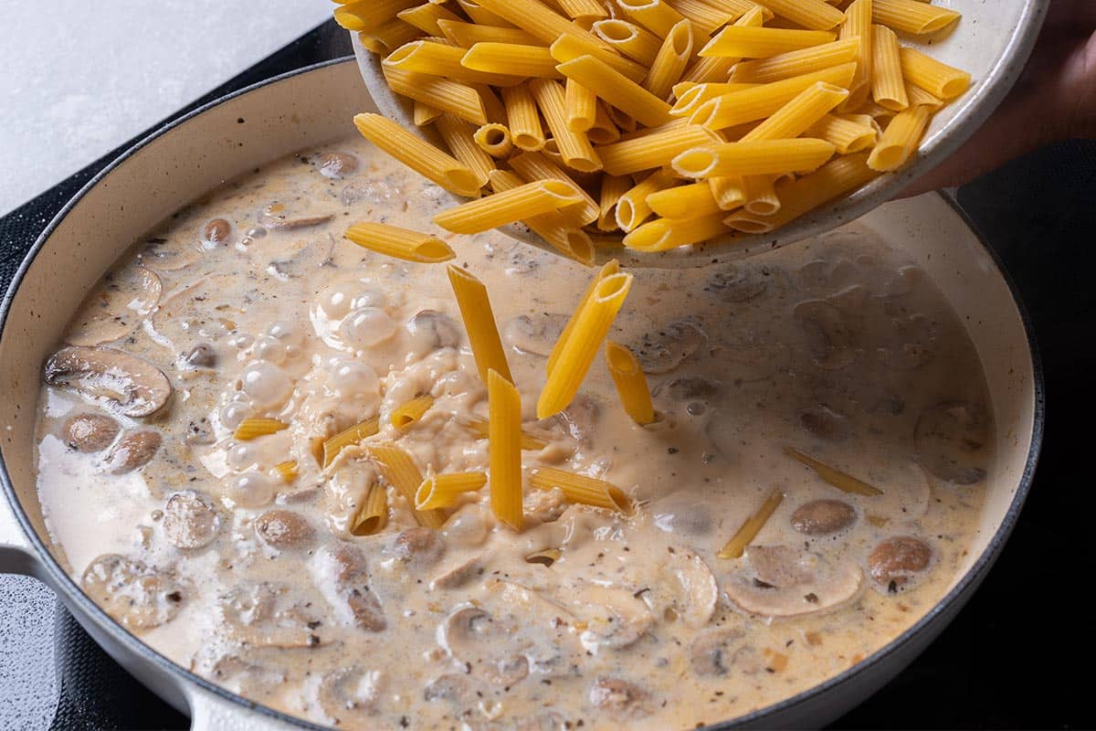 creamy mushroom sauce with penne being poured in