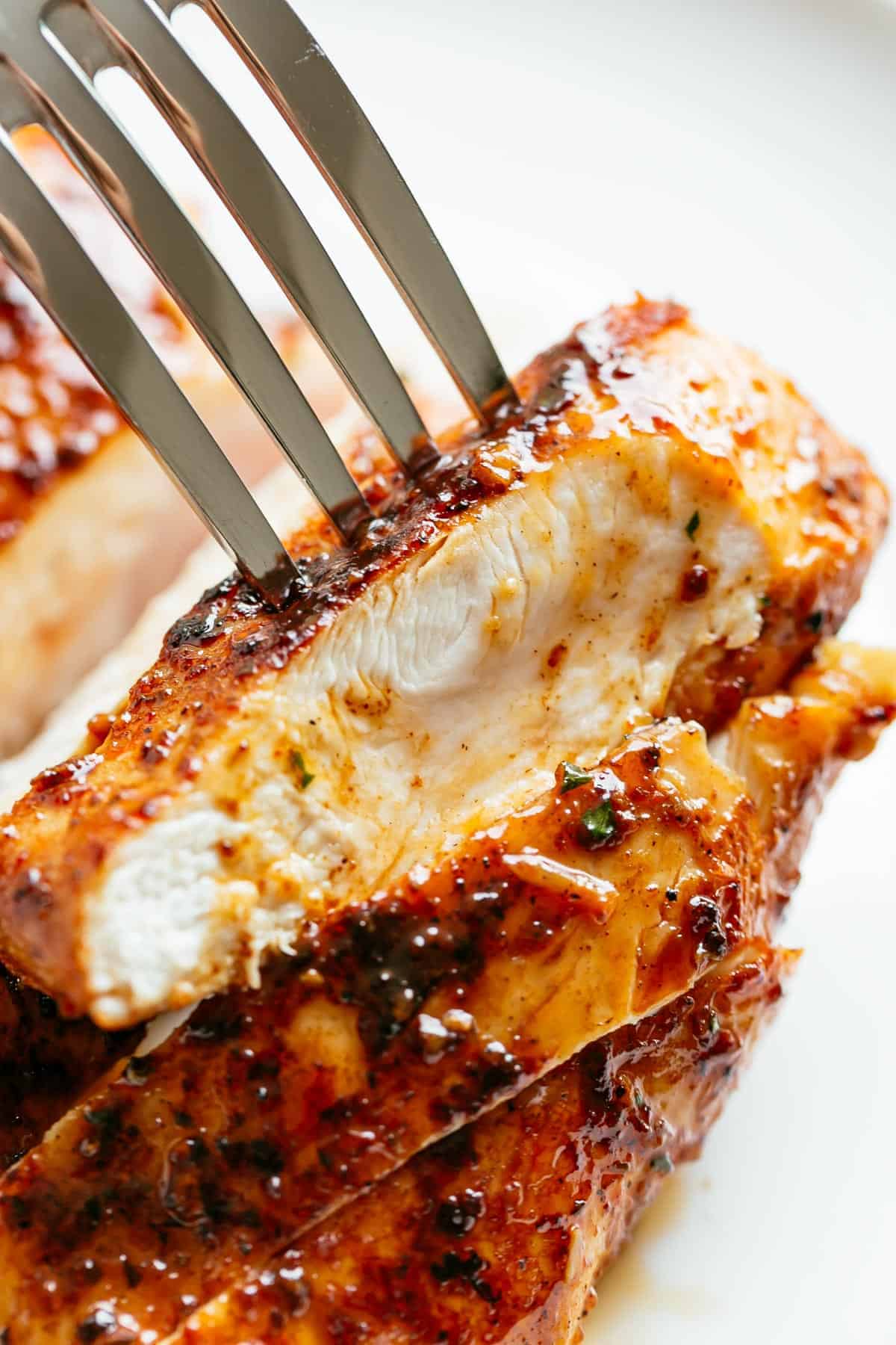 The inside part is a juicy piece of baked chicken breast. A fork pierces the top.